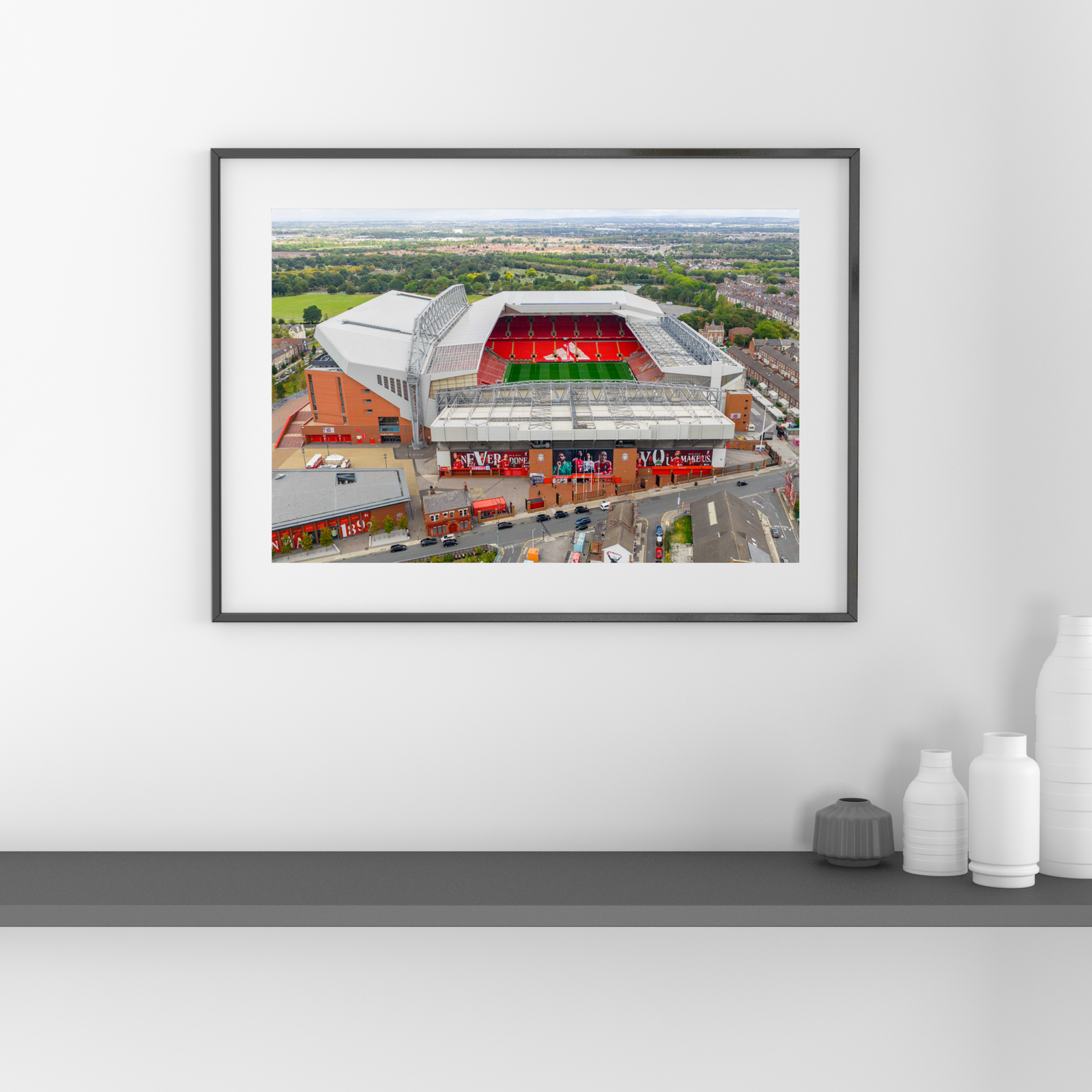 Aerial view of Anfield Stadium in Liverpool, England, featuring the iconic red seating of Liverpool FC surrounded by residential neighbourhoods and green parkland.
