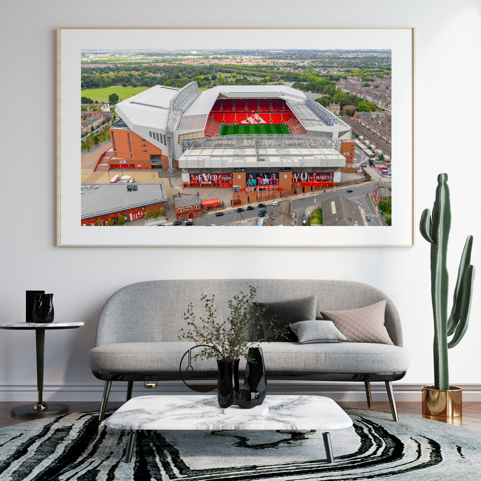 Aerial view of Anfield Stadium in Liverpool, England, featuring the iconic red seating of Liverpool FC surrounded by residential neighbourhoods and green parkland.