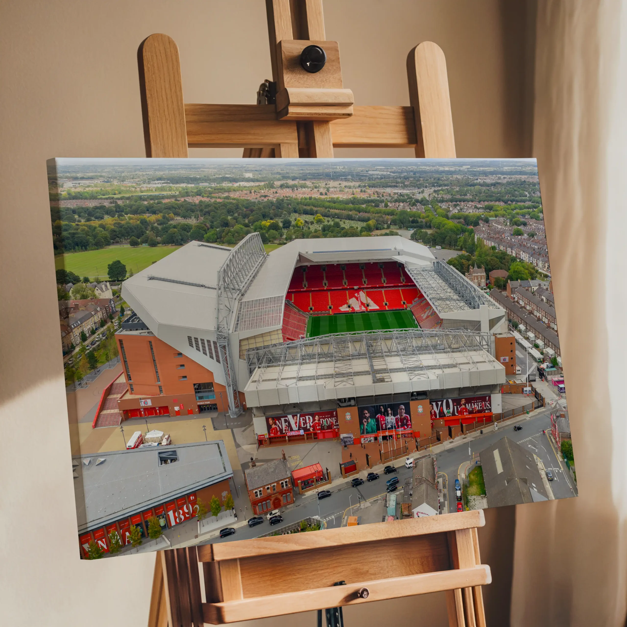 Aerial view of Anfield Stadium in Liverpool, England, featuring the iconic red seating of Liverpool FC surrounded by residential neighbourhoods and green parkland.